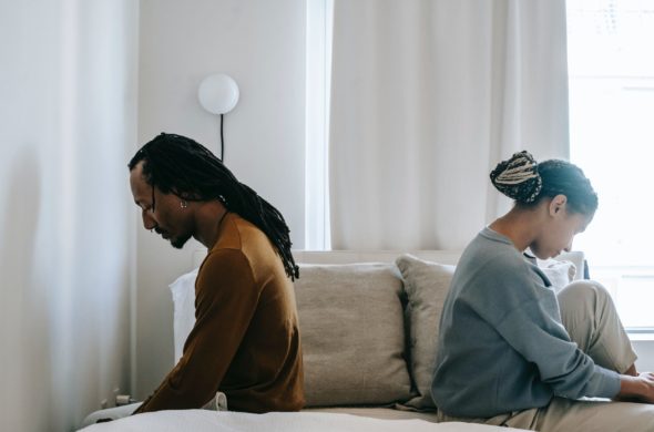 african american couple sitting on bed facing away from one another