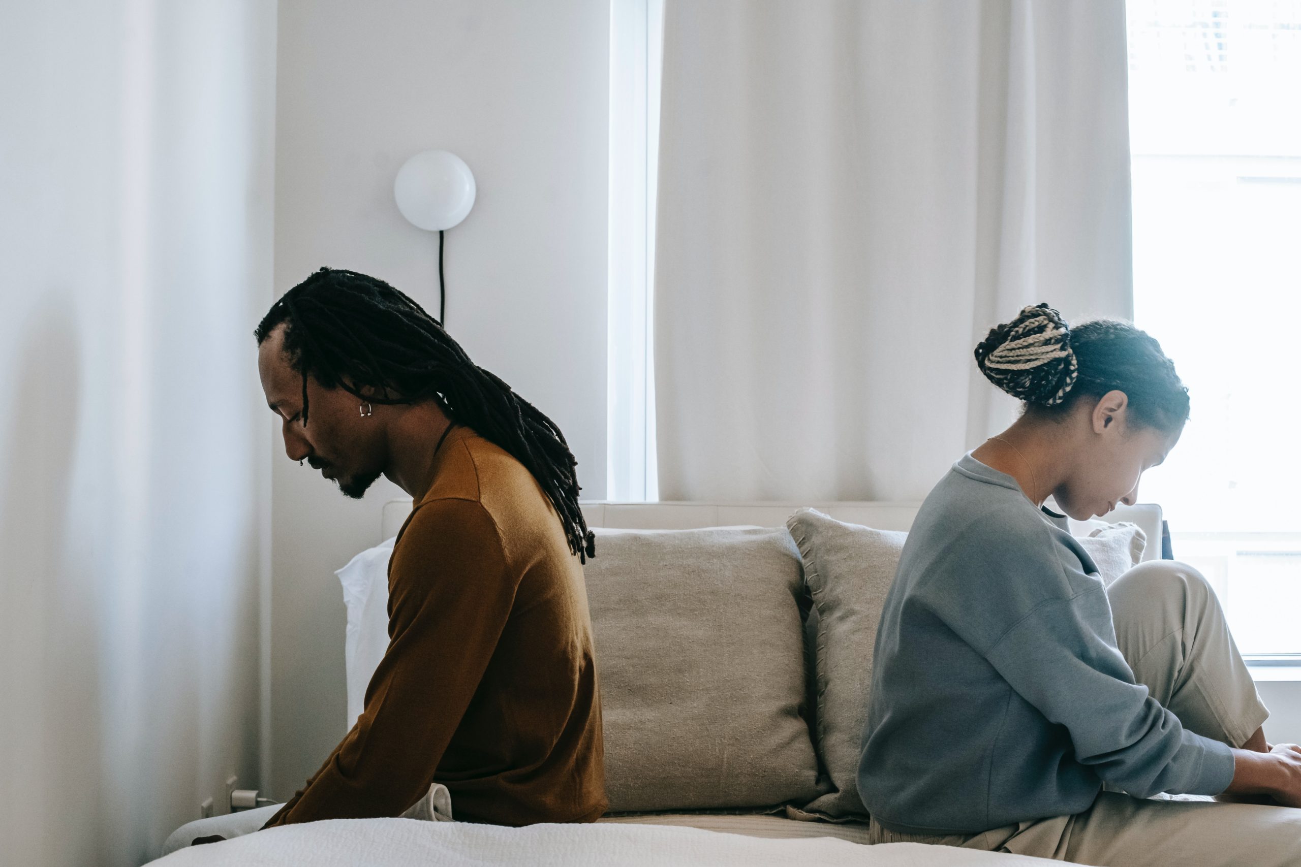 african american couple sitting on bed facing away from one another